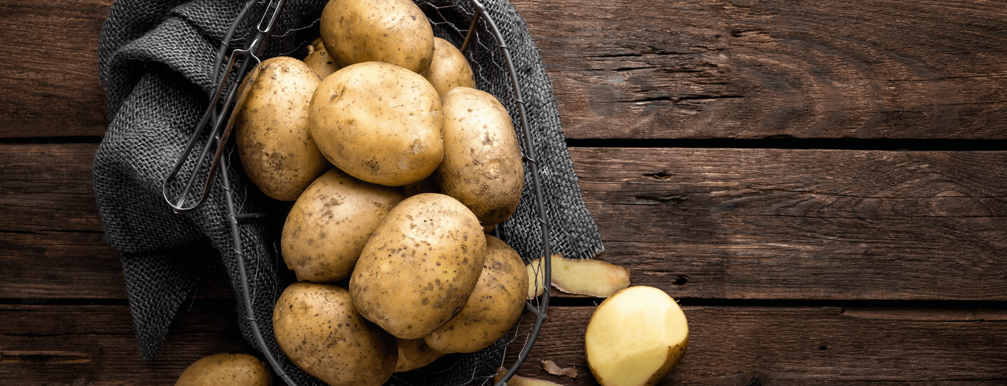 Peeled and unpeeled potatoes laying on table